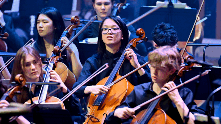 NYO cello players performing on the Barbican stage.