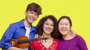 Three young musicians smiling together.